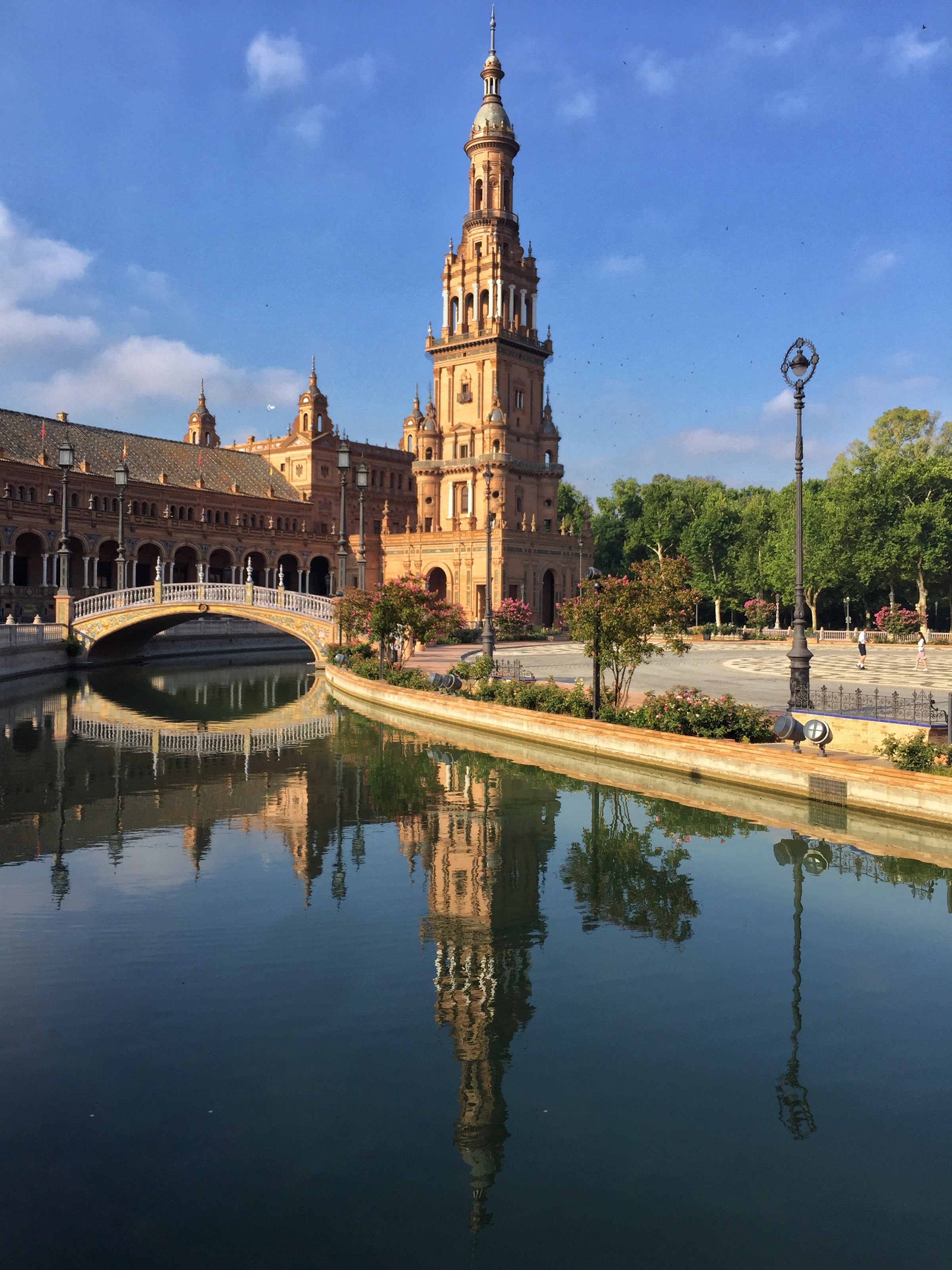 Plaza de Espana, Sevilla. Ein Gebäude und eine Brücke spiegeln sich im Wasser.