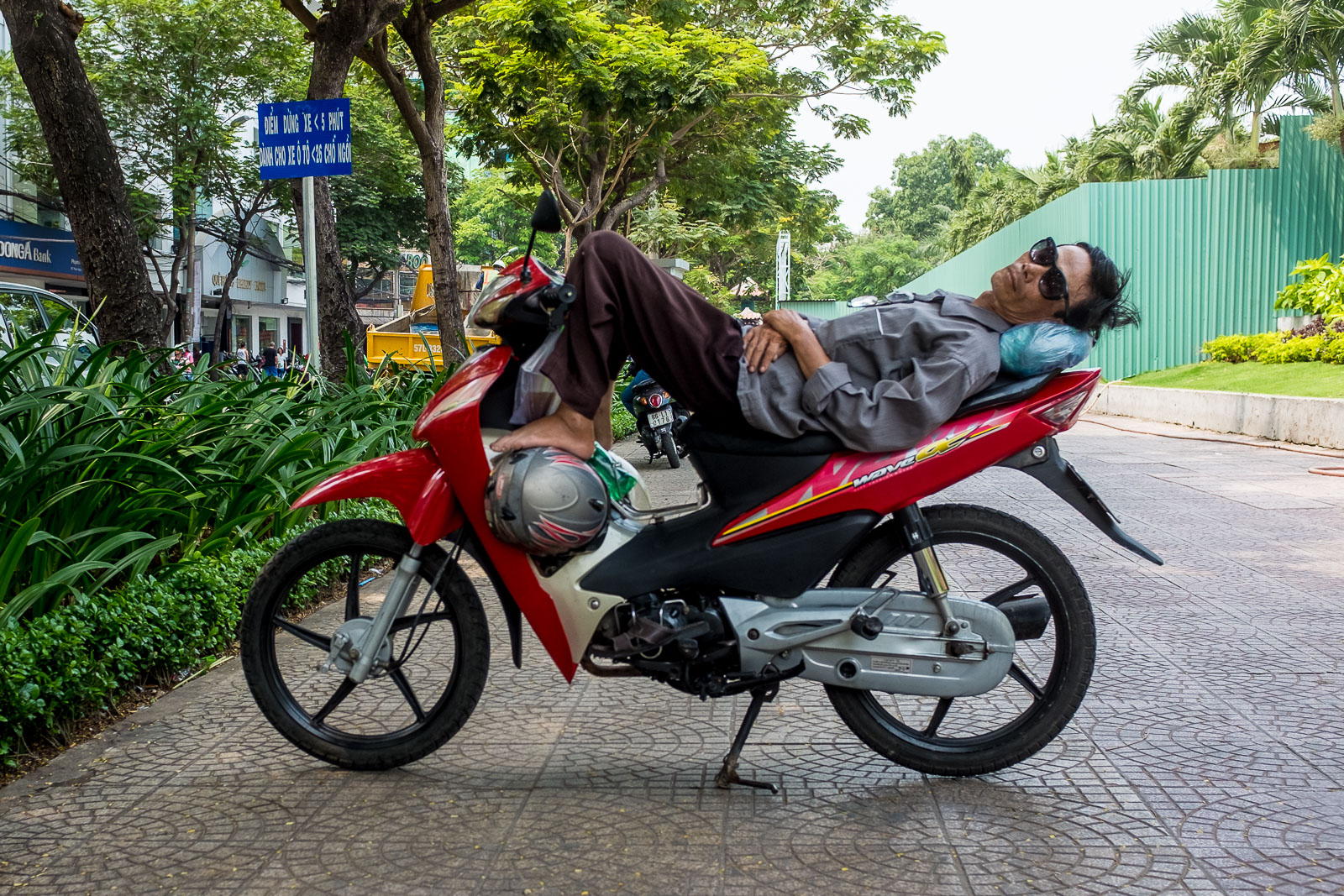 Ein Vietnamese schlafend auf seinem Motorrad.